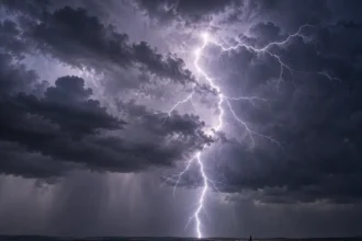 A bright, branching lightning bolt beneath dark thunderclouds over a distant town.